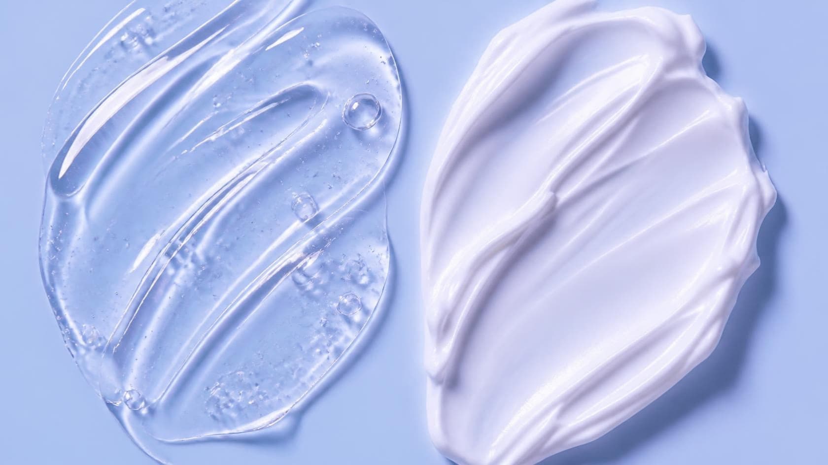 A clear gel swipe beside a thick white cream swipe on a glossy powder-blue surface.
